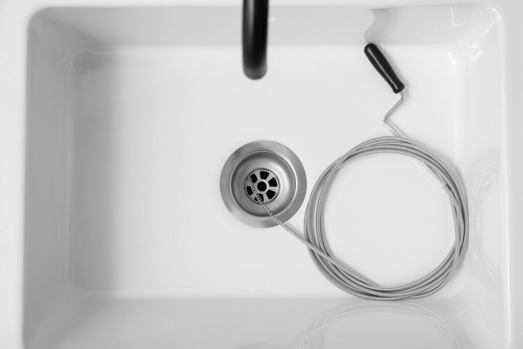 Drain snake coiled in a white sink beside the drain