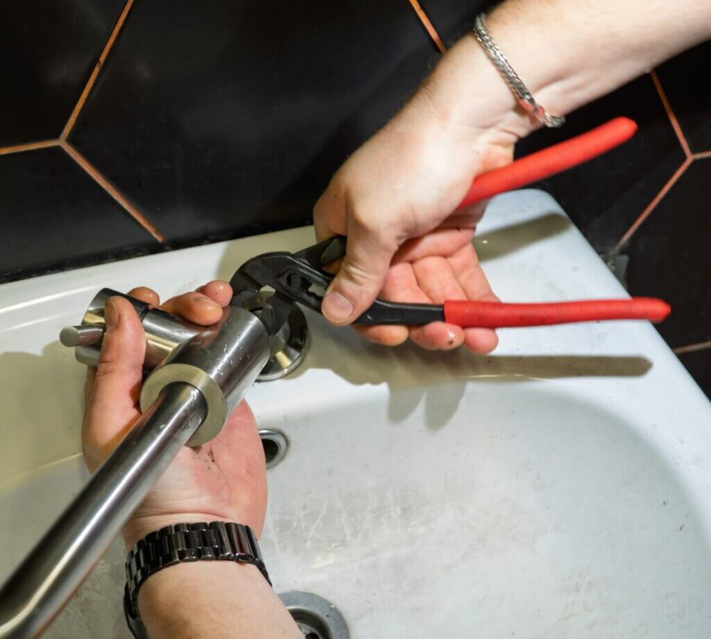 Hands fitting a faucet with pliers