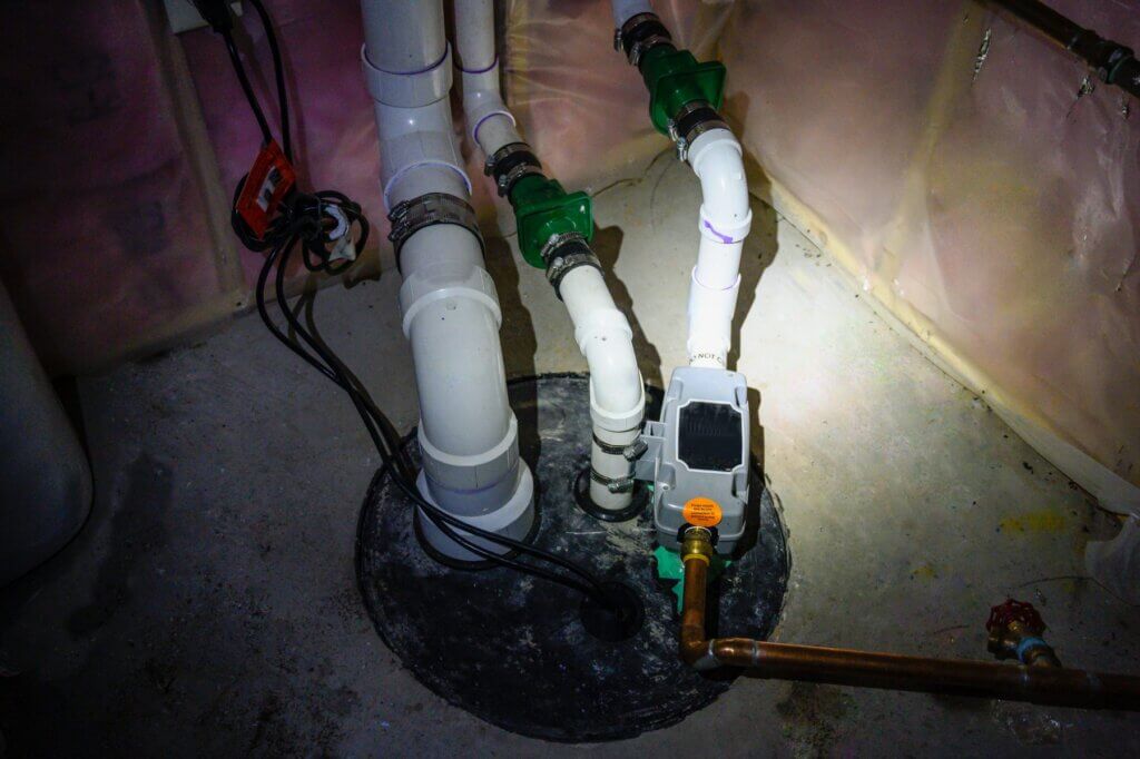 Sump pump and discharge pipes in a basement pit